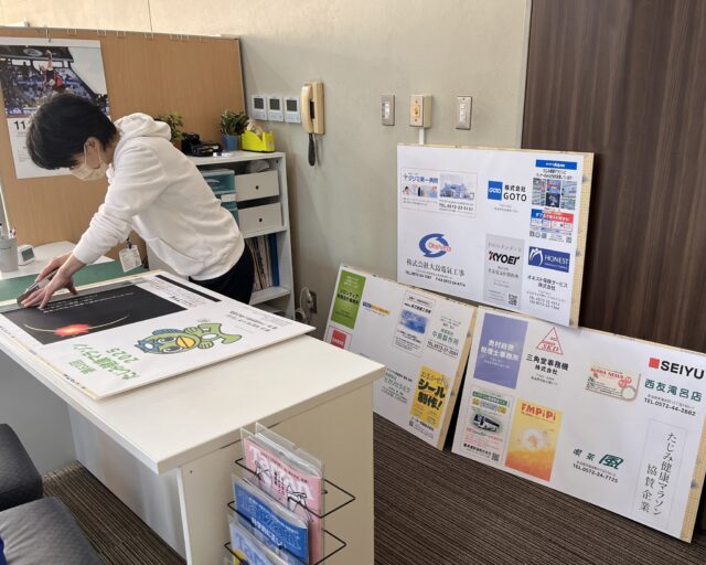 たじみ健康マラソン　協賛企業パネル

今回のマラソン大会に、多くの企業様からご協賛をいただきました。
多大なるご厚意を賜り、誠にありがとうございます。
当日に協賛企業様を宣伝すべく、現在パネルを作成中です。

作業するスタッフの名札を、ご覧ください。
　　👈見えないと思うけどね
彼女の名札は何と「大谷翔平」です🤪

その自称・翔平ちゃんが「しまった～💦」と大声で事務所に入ってきました。どうやら、カットラインを間違えたらしいです🤣　
あら大変！だけど広告自体には影響がないので、そのままにしてあります…

どこが間違っているか、大会当日にぜひ現物でご覧ください😉-☆

マラソン大会まであと１週間‼
まだまだいろんなハプニングが起きる予感😰
　
　
　
 #多治見 #多治見市 #多治見市スポーツ協会 #tasa 
 #たじみ健康マラソン #たじみ健康マラソン大会 #たじみ健康マラソン2025 
#ただいま準備中
　
　

#ハプニング #実はすでに発生
#この期に及んで #プリンター壊れた疑惑
#真剣に困るやつ